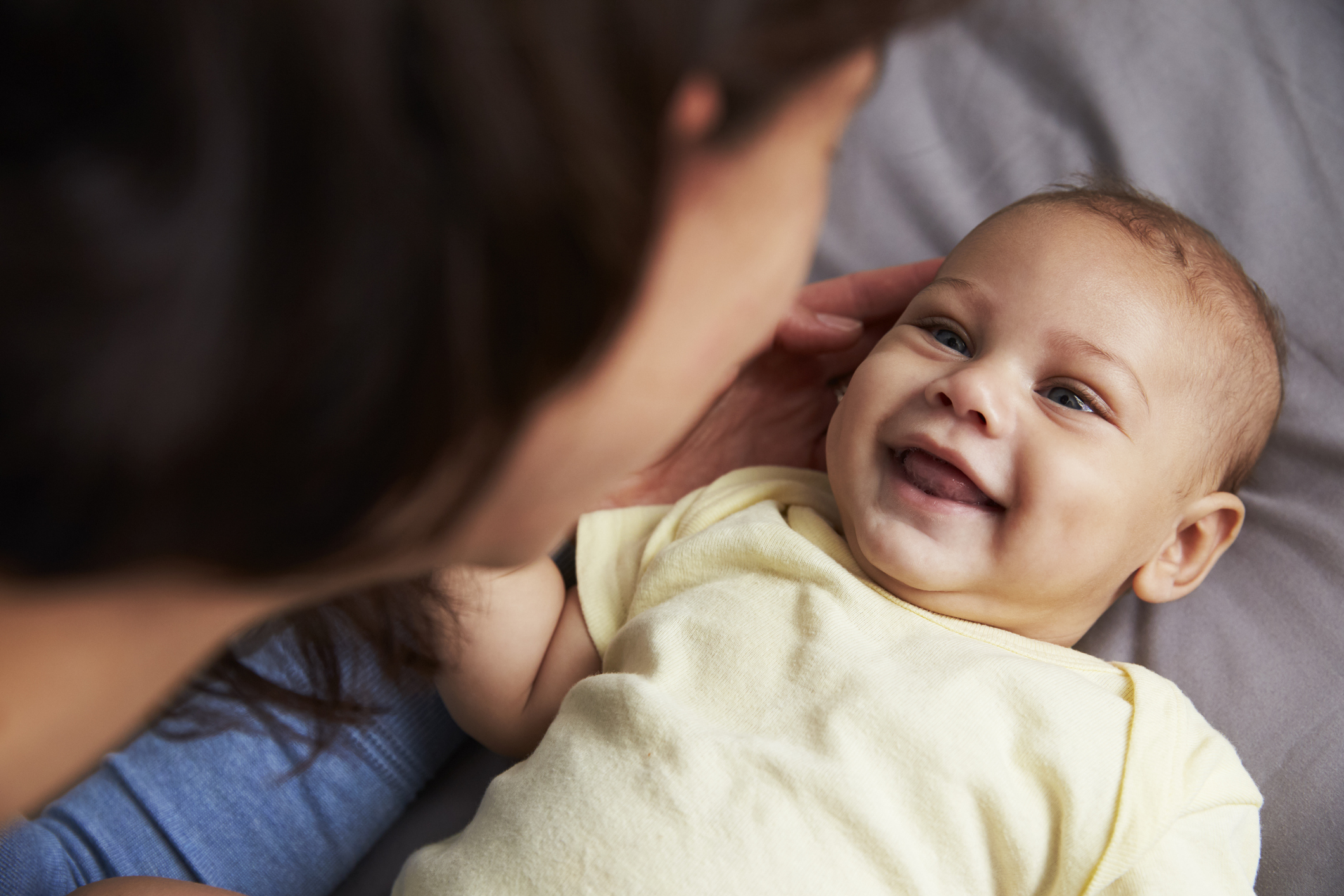 A baby smiles happily at their parent