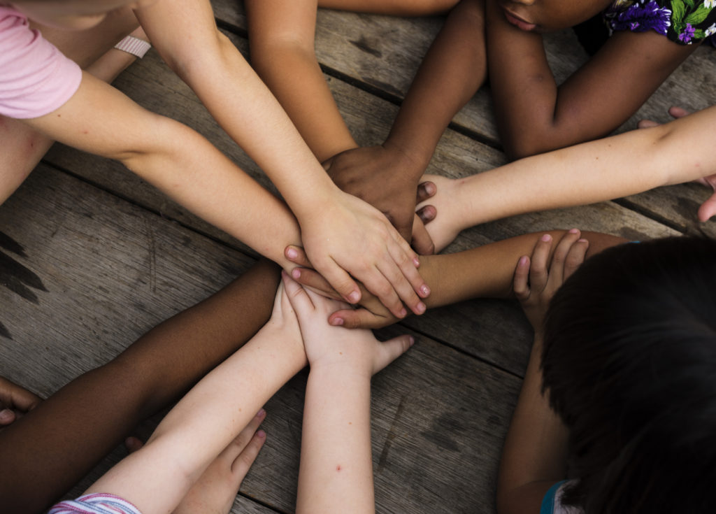 People of various skin colors all putting their hands together