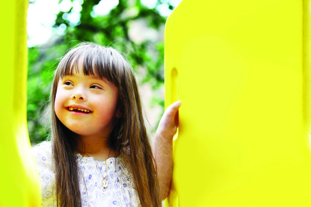 A smiling young girl with long brown hair and a missing tooth