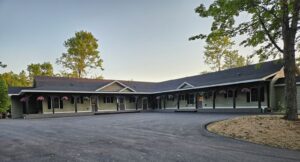 Exterior of the Stay & Play Child Care Center in Lyndonville, VT, showing sage-green siding and hanging flower baskets