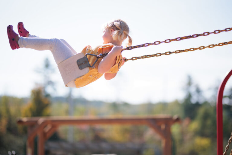 Young child swinging high on swing