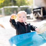 A toddler with blond hair holds up an apple