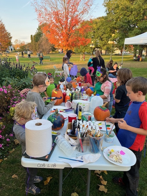 Children paint pumpkins outdoors at Fall Fun Fridays in Lyndonville