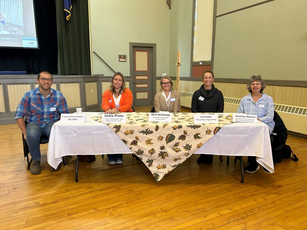 Five Early Childhood Summit presenters smiling while seated at a table facing the camera