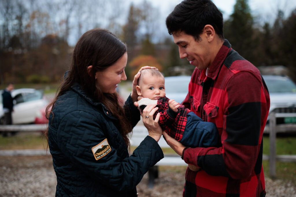 Two parents holding, looking at, and smiling at an infant