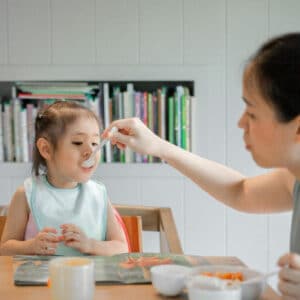 A mother feeding a young child with a spoon