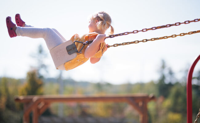 Young child swinging high on swing