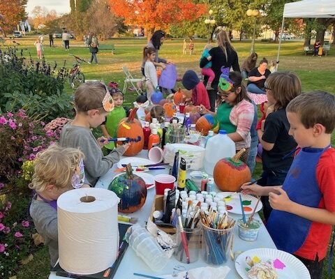 Children paint pumpkins outdoors at Fall Fun Fridays in Lyndonville