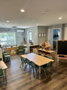 Interior of Stay & Play Child Care Center showing books, toys, a chalkboard, tables, and chairs