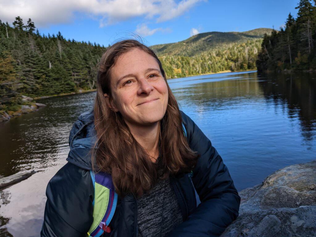 Jenn Schollmeyer smiling with a lake and mountains in the background