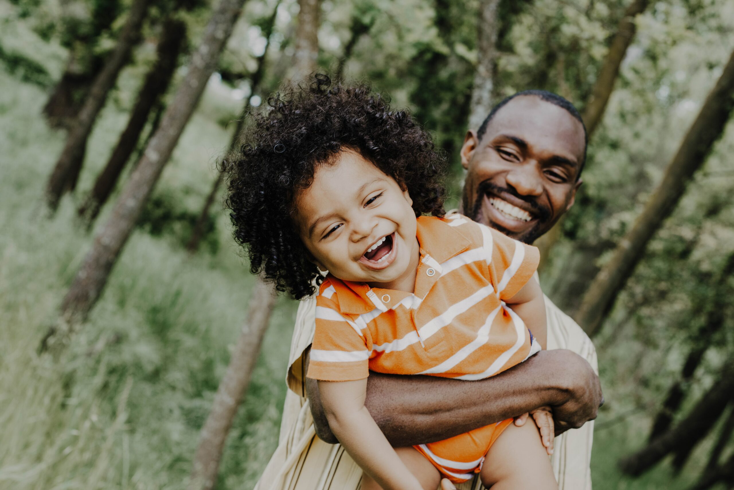 Father holding young child, both of them smiling