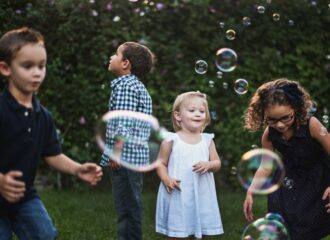 Four young children playing with bubbles