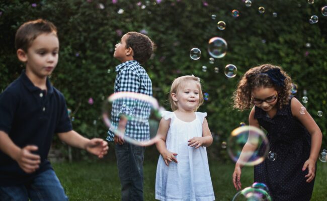 Four young children playing with bubbles