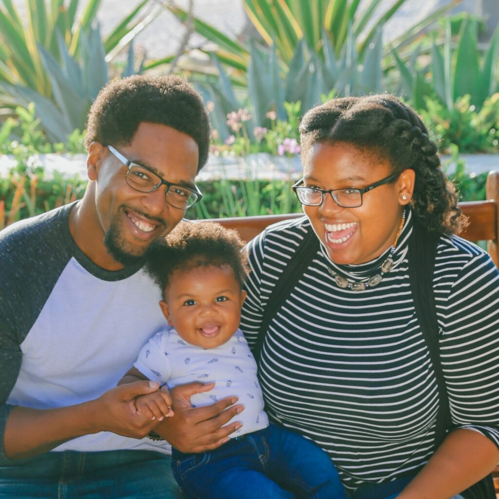 Black parents holding their toddler and smiling happily