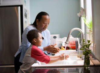 Parent and child washing hands at kitchen sink