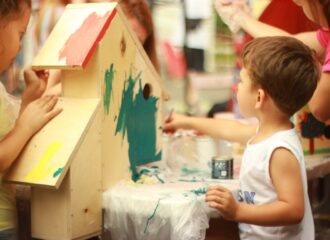 A preschooler painting a bird house
