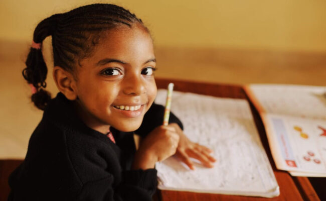 Young student smiling and holding a pencil