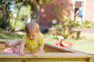 Young child climbing out of sandbox